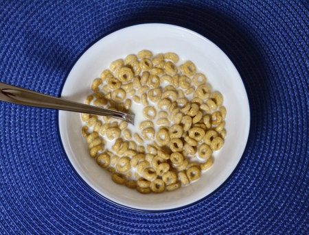 A top view of cereal with milk in the bowl on the blue surfaceの写真素材