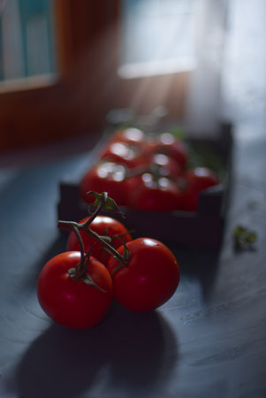 Fresh tomatoes illuminated by the light coming through the window, on a blue background.の写真素材