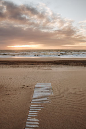 A vertical shot of beautiful sunset over a coastline with sandy beachの写真素材