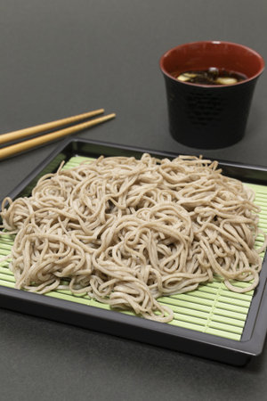 A plate of Japanese buckwheat noodles named soba with soy sauce and chopsticks