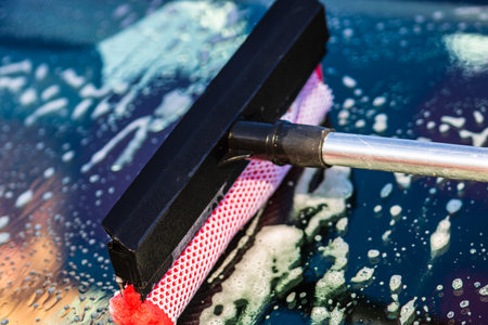 Washing and cleaning the front window of a car with mop in self service car wash station, close up isolated.の写真素材