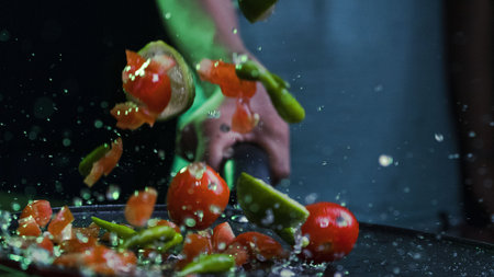 A closeup shot of slices of lime and cherry tomatoes with water droplets on a black plateの写真素材