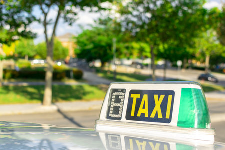 An illuminated "TAXI" sign on a cab parked in the parkの写真素材