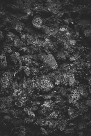 Closeup of dark rock textured background. Gray rough stone texture and background for design. Black...