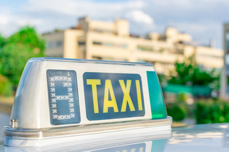 An illuminated "TAXI" sign on a cab with a block of buildings in the backgroundの写真素材