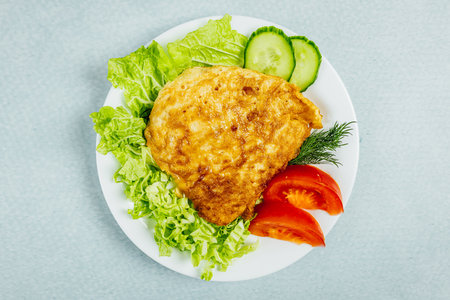 A closeup of a delicious potato pie served with dill, tomatoes, and lettuce on a turquoise surfaceの写真素材