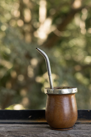 A Mate caffeine-rich infused drink in a palo santo wood cup with a metal straw put on a wooden sillの写真素材