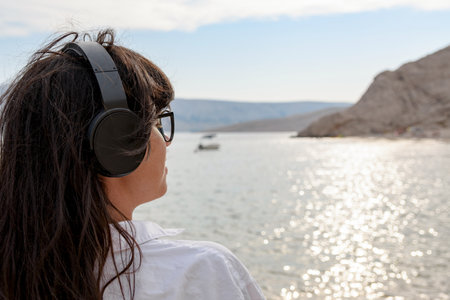 Side view of young woman with eyeglasses enjoying while listening to music on beach.の写真素材