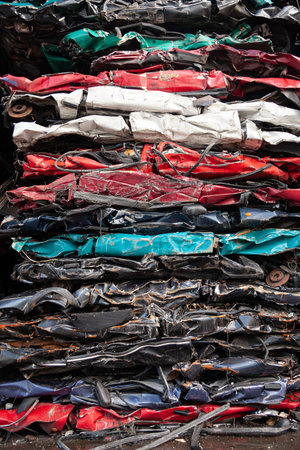 Compacted vehicles as a stack in different colors from a car recycling center.
