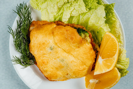 A closeup of a delicious cabbage pie served with dill, lemon, and lettuce on a turquoise surfaceの写真素材