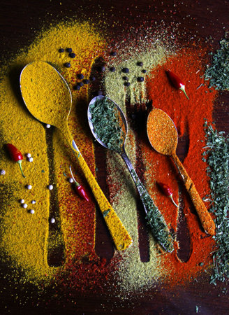 A top view of metal multisized spoons arranged next to each other covered with different spicesの写真素材