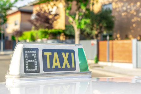 An illuminated "TAXI" sign on a cab parked in front of a houseの写真素材