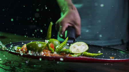 A closeup shot of slices of lime and vegetables with water droplets on a black plateの写真素材