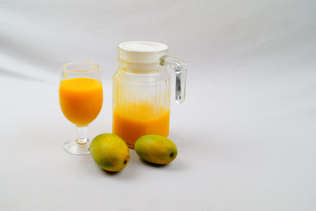 A high angle shot of mangos, a pitcher, and a glass of fresh mango juiceの写真素材