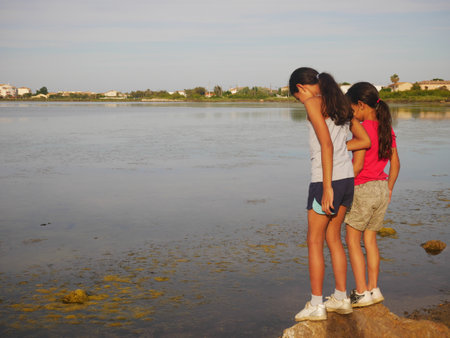 Photo of sisters the edge of a pond during the sunsetの写真素材