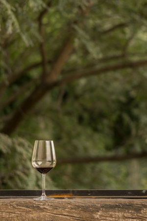 An almost empty glass of red wine put on a wooden window sillの写真素材