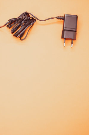 A vertical shot of wired charger adapter isolated on orange backgroundの写真素材
