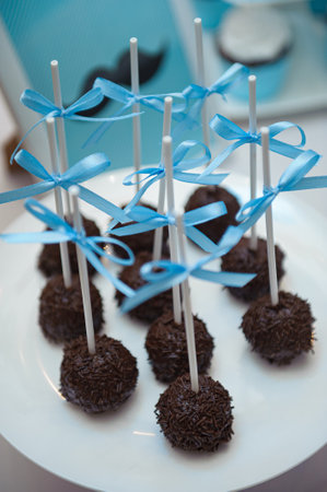The chocolate cake pops on the plate with blue ribbons