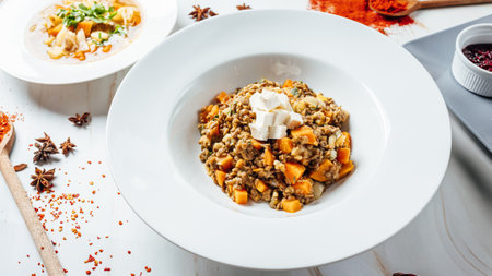 A delicious meal with chickpeas, beans, pumpkin and cheese served in a white bowの写真素材