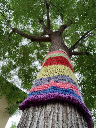 A vertical shot of yarn bombing on a high tree with green leaves in the backgroundの写真素材