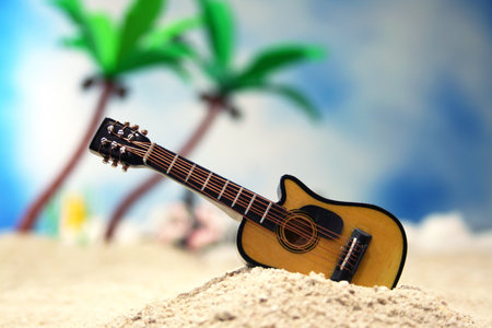 A closeup shot of a guitar on a tropical beach sand in a studio
