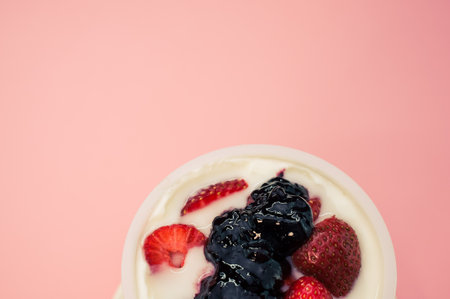 A top view of yogurt with strawberries and blueberry jam isolated on pink backgroundの写真素材
