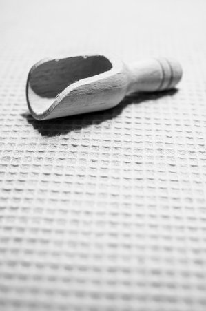 A vertical grayscale shot of a wooden scoop on a surfaceの写真素材