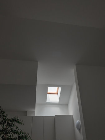 A vertical shot of the inside of a simple modern house with a small window on the ceiling