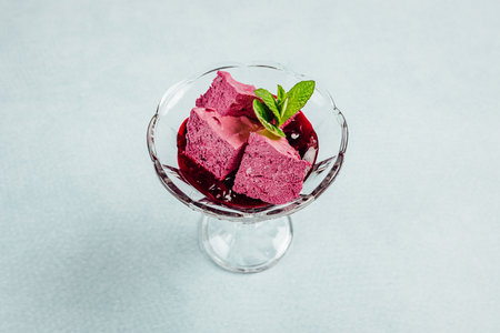A closeup shot of a refreshing dessert with pomegranate jam on a turquoise surfaceの写真素材
