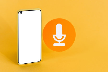 A smartphone with a blank white screen and a paper microphone icon on a pastel background - Communication and voice messaging conceptの写真素材