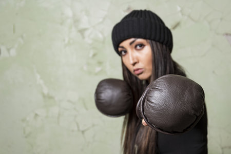 A young brunette girl is engaged in mixed martial arts. Model's face is out of focus. Looks into the camera. Preparing for the main competition in lifの写真素材