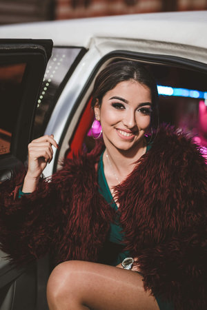 A young pretty Caucasian girl sitting in the back seat of a limousine with her legs outsideの写真素材