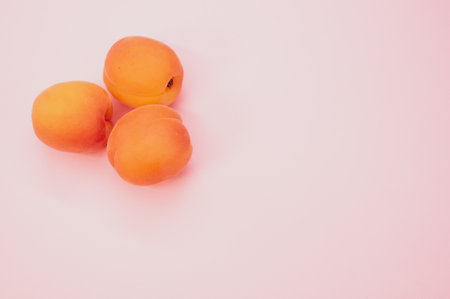 A high angle shot of fresh three apricots isolated on pink backgroundの写真素材