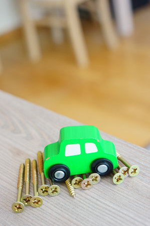 A closeup of a green painted wooden car toy on metal screwsの写真素材