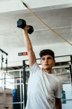 Young athlete lifting dumbbells in the middle of a workoutの写真素材