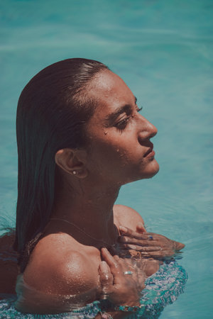 A black girl relaxing by the pool in her flat while she looks away on a sunny day. Summer vibes concept 2021.の写真素材