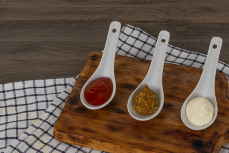 spoons three sauces ketchup mayonnaise mustard white backgroundの写真素材