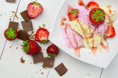 Ice cream with strawberries and chocolate on white wooden tableの写真素材