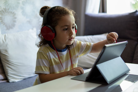 Little Boy in headphones using tablet sitting in the livingroom