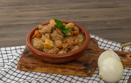 beef stew in earthenware casserole and wooden boardの写真素材