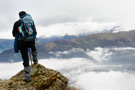 Landscape view of hazy autumn mountain hills and standing hiker with backpack in foreground and enjoyingの写真素材