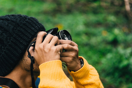 Portrait of a young adult man holding a camera and taking a picture. photography and film concept.