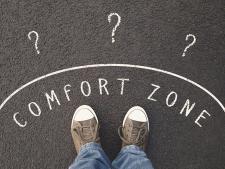 feet of unrecognizable person standing on street with chalk text on asphalt - leaving comfort zone conceptの写真素材