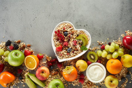 Top view of appetizing breakfast bowl with fresh berries and oat placed on table with arranged various fruitsの写真素材