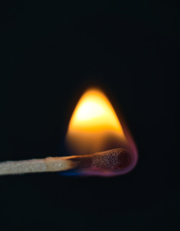 A selective focus of a match on fire on black backgroundの写真素材