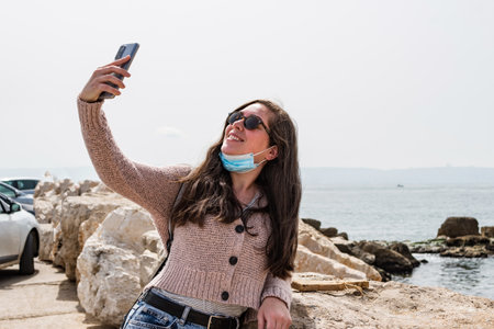 Happy casual woman photographing a selfie on the beach enjoying holidays and laughing.
