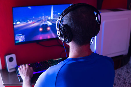 Young man with headphones playing videogames on a gamer desktop computerの写真素材