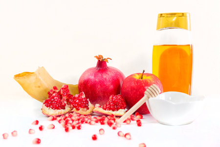 Whole pomegranate, pomegranate seeds, red apple, ram's horn and honey, on white background. Jewish New Year symbols.の写真素材