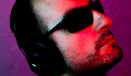 Neon portrait of a caucasian man wearing sunglasses and with headphones listening to music. Listen...