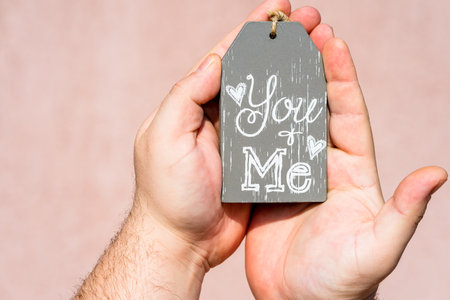 Hands holding ornament with text message you and me
